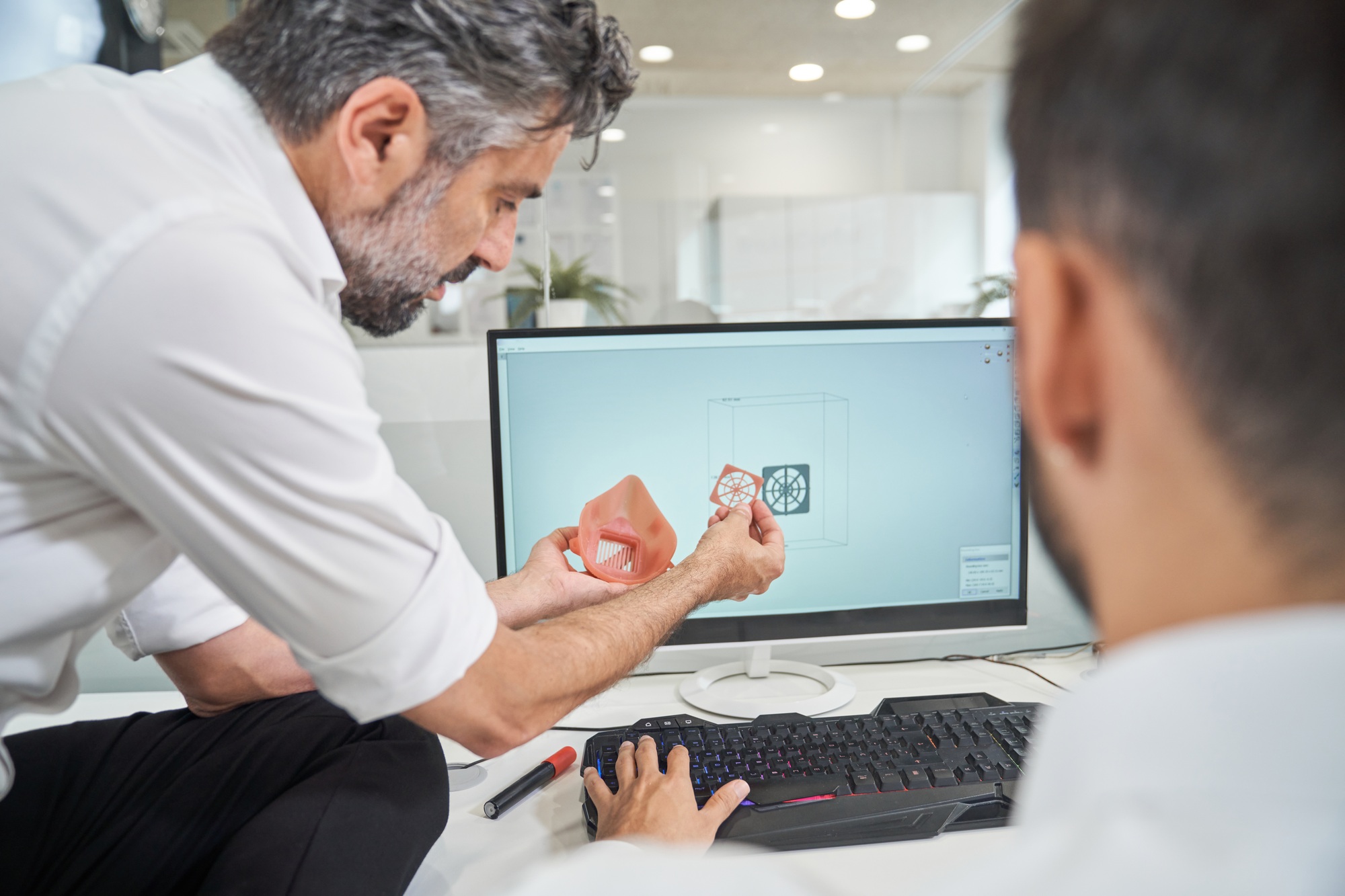 Engineers with 3D model of respirator near computer